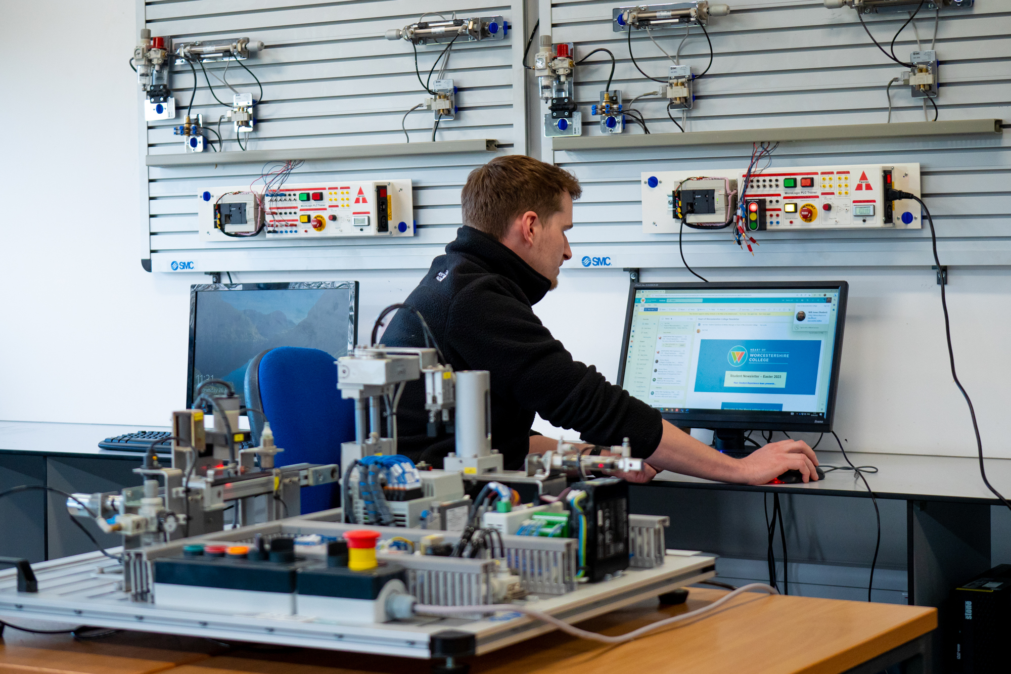 Engineering student works on computer with wires behind him