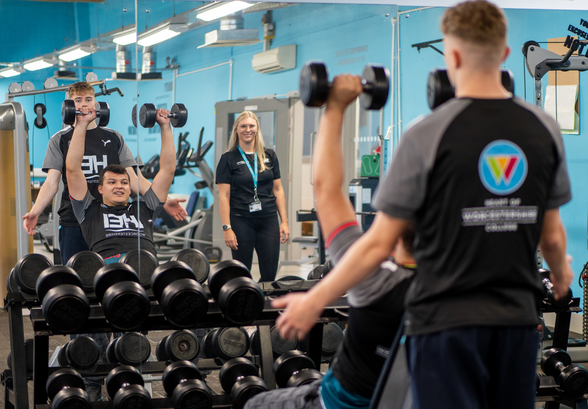 Sports students in a gym using dumbbells