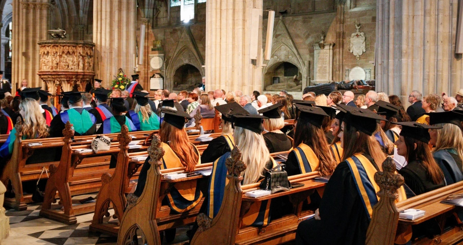 students in cap and gowns sat in cathedral