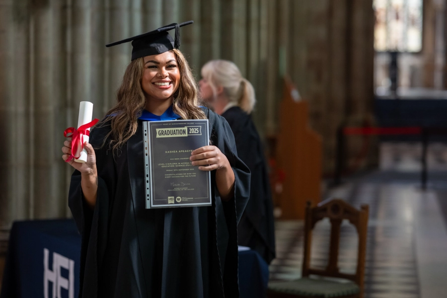 Graduate holding up scroll and certificate in the Cathedral with Cap and Gown on