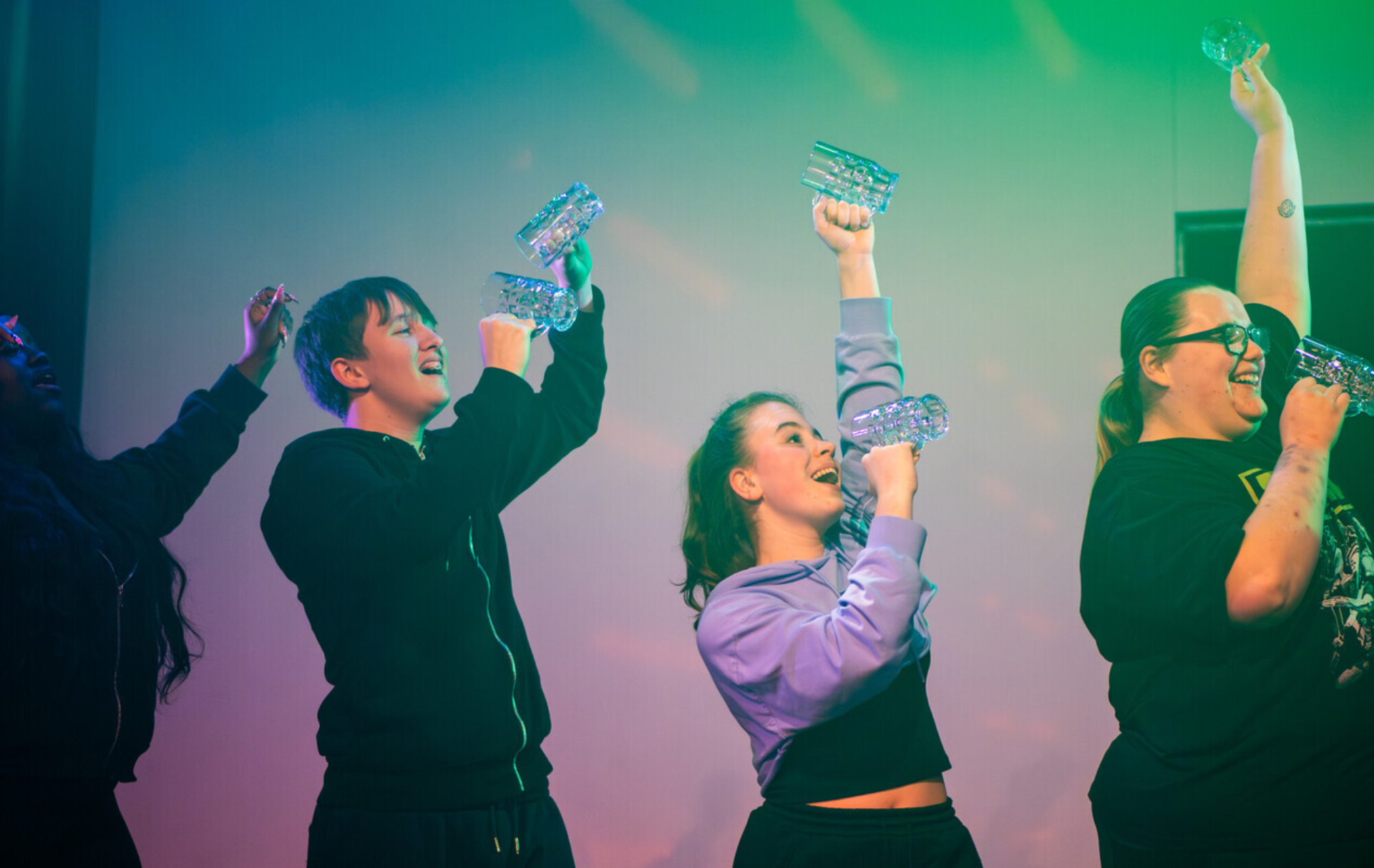 Three performers stand together on a stage