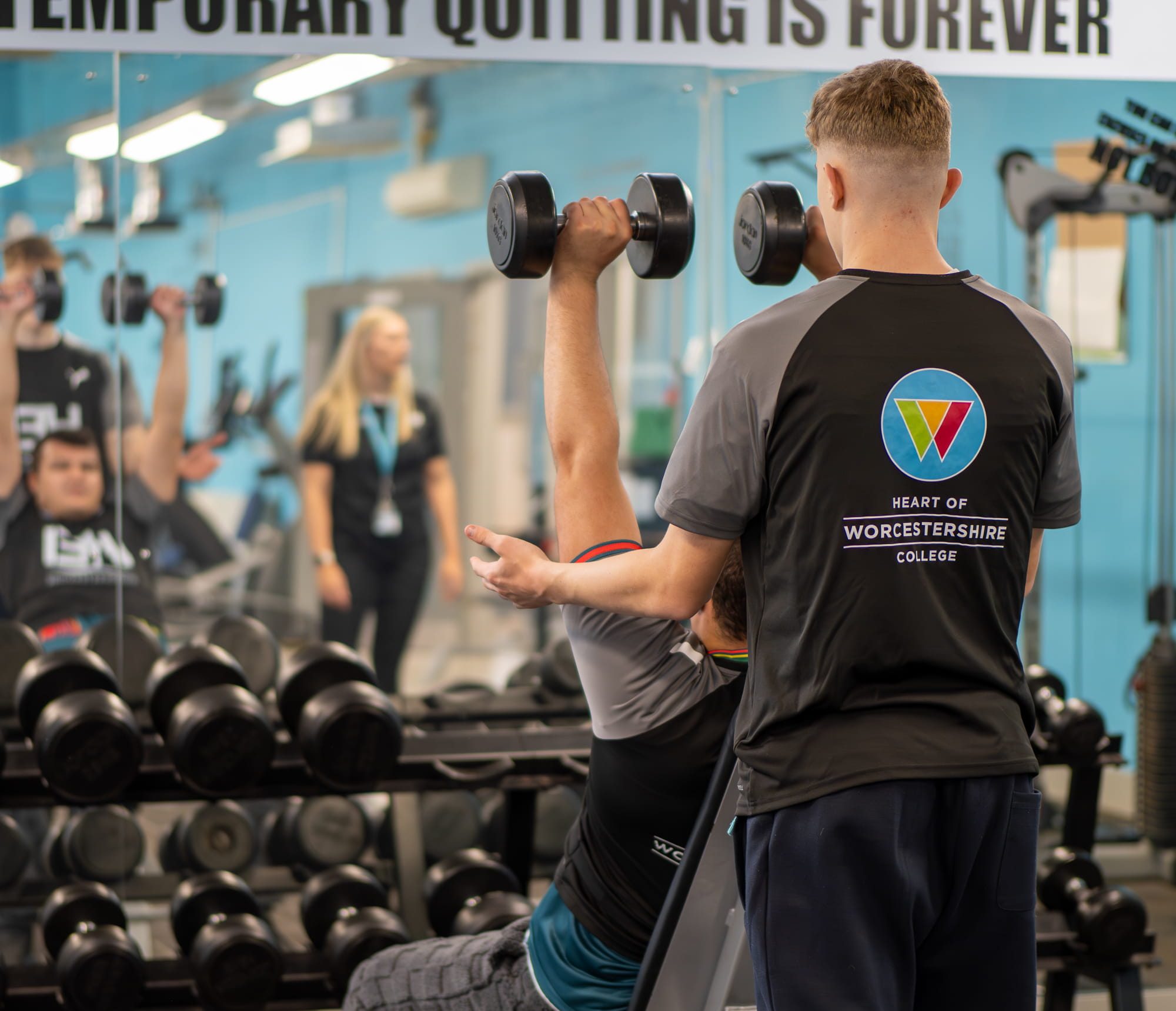 A student supporting another student lifting weights