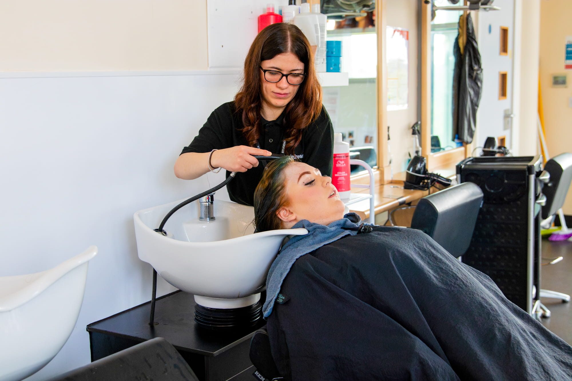 Girl having hair washed by student