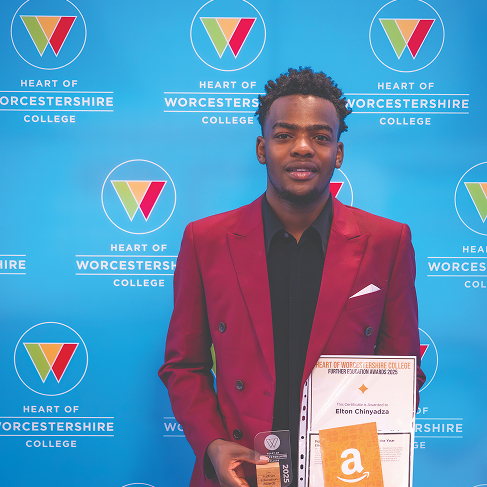 Student with award stood in front of back drop smiling
