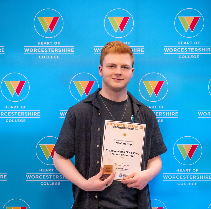 Student stood in front of HoW College backdrop holding their certificate and trophy