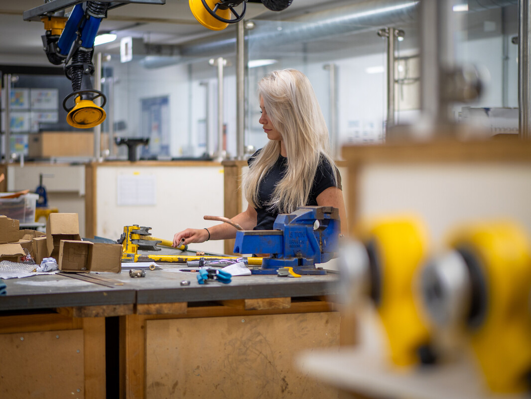 A female student working at a bench in a construction workshop