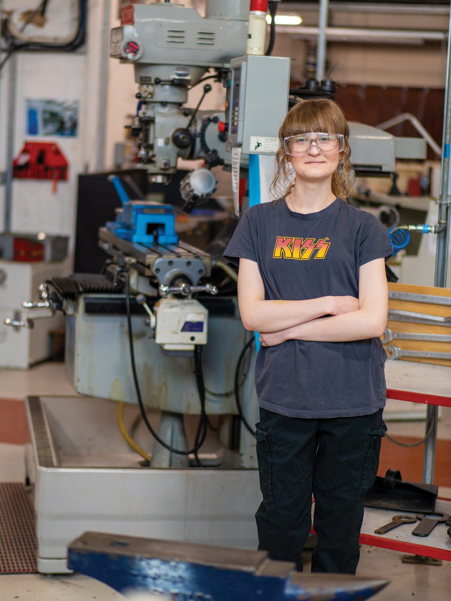 Student standing in front of engineering machinery in workshop
