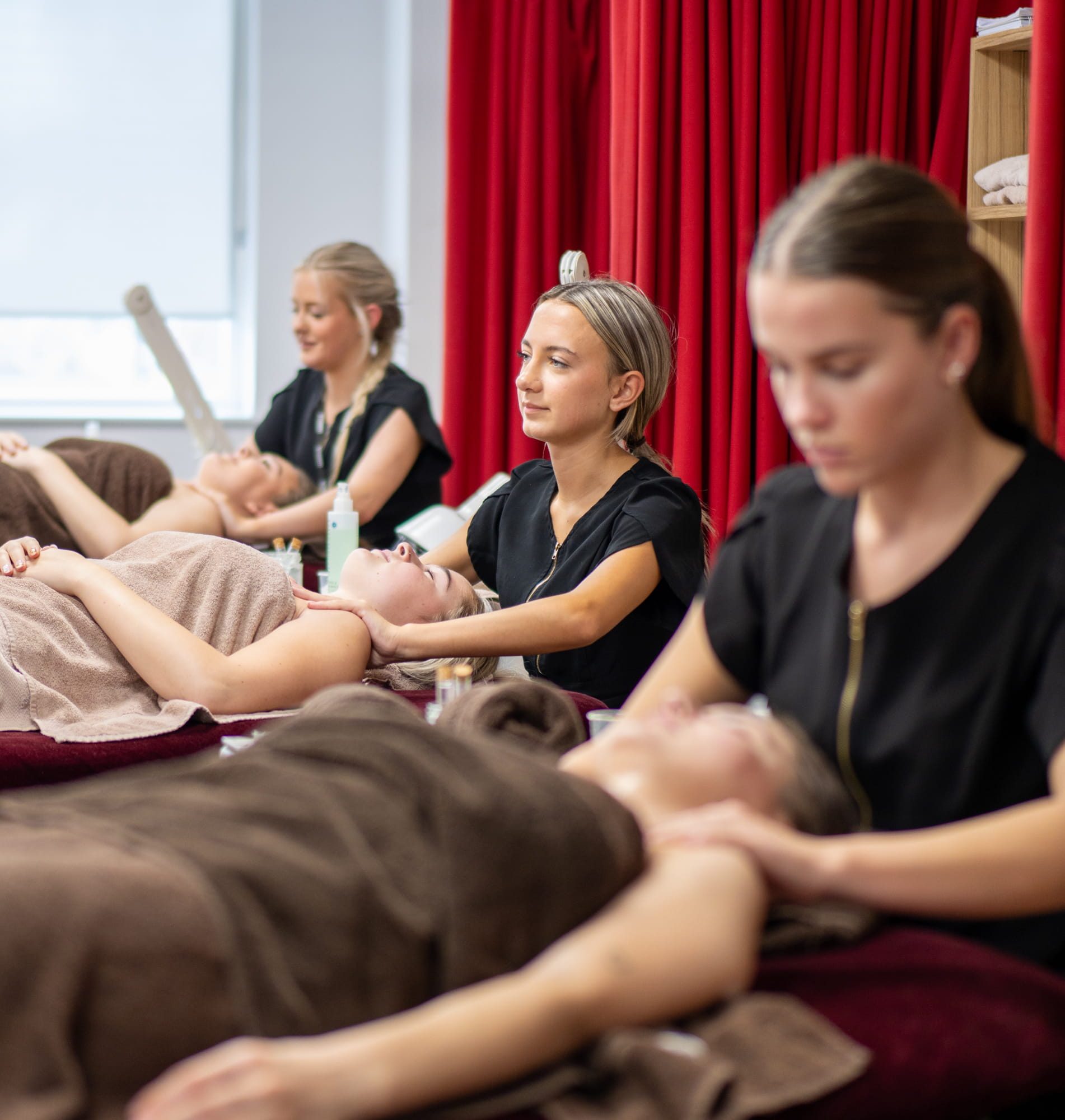 Three students sat in a row giving neck massages