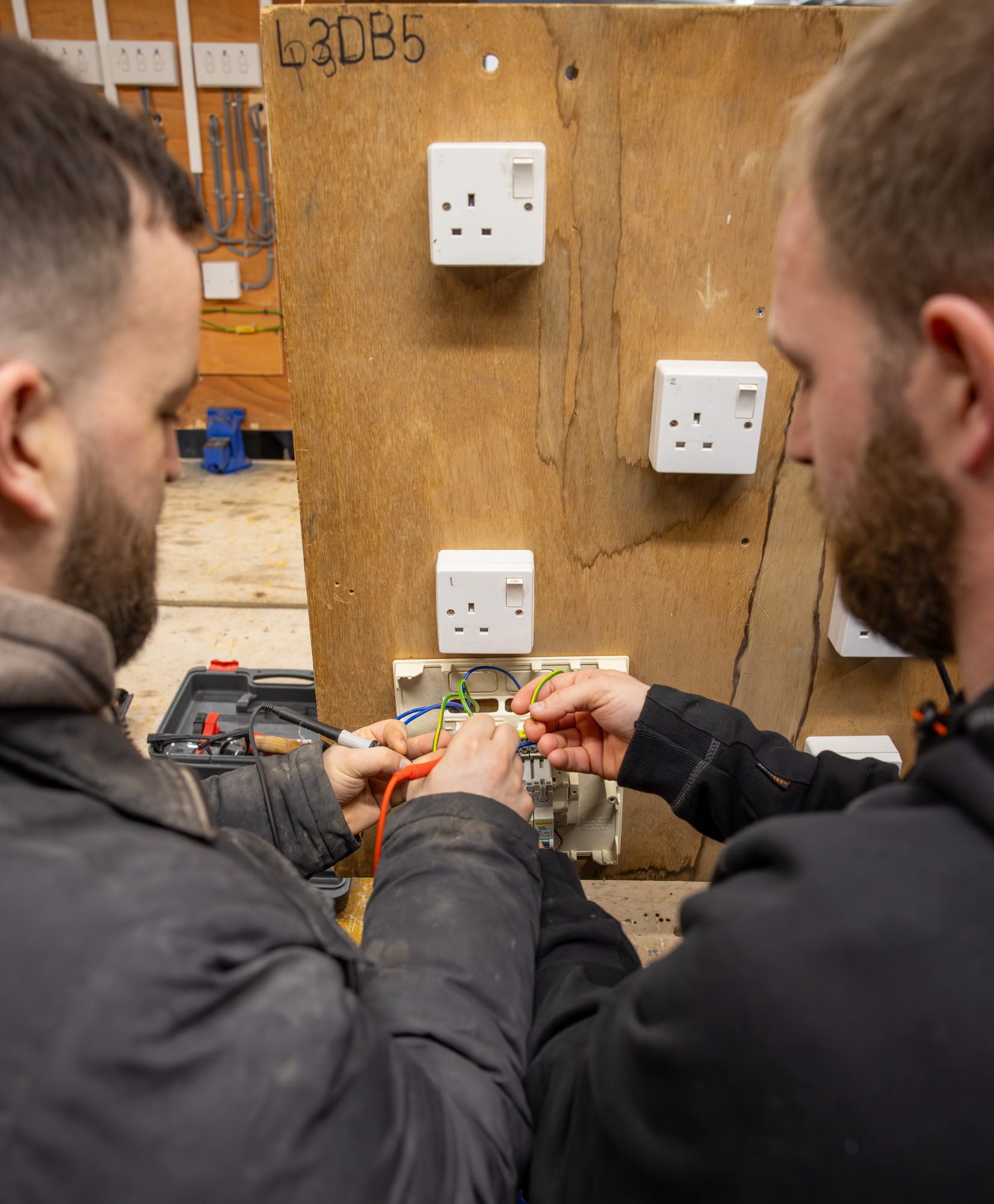 Two students helping eachother wire a socket