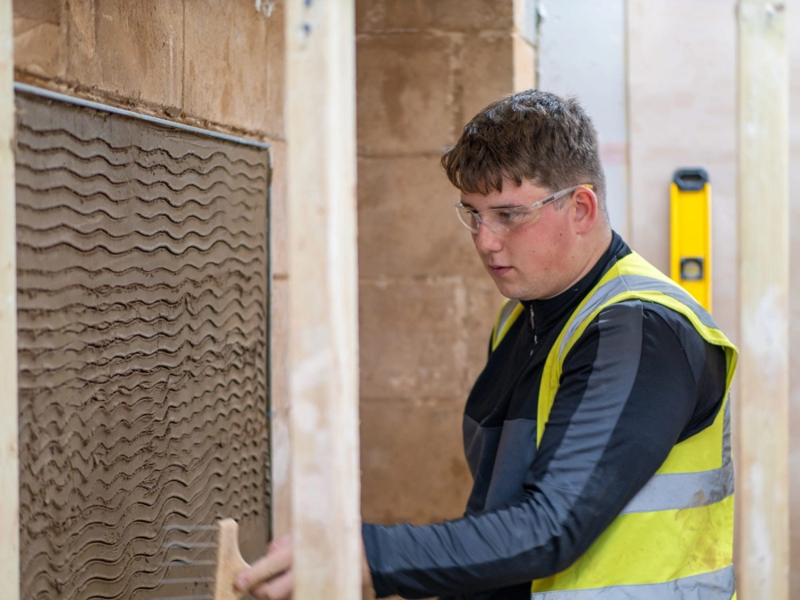 Student cementing a wall in workshop