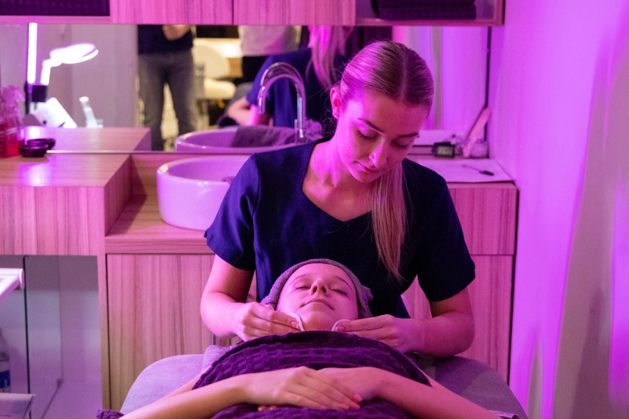 Student in a salon giving someone a facial