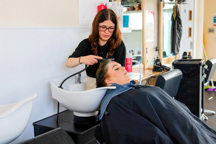 Girl having hair washed by student