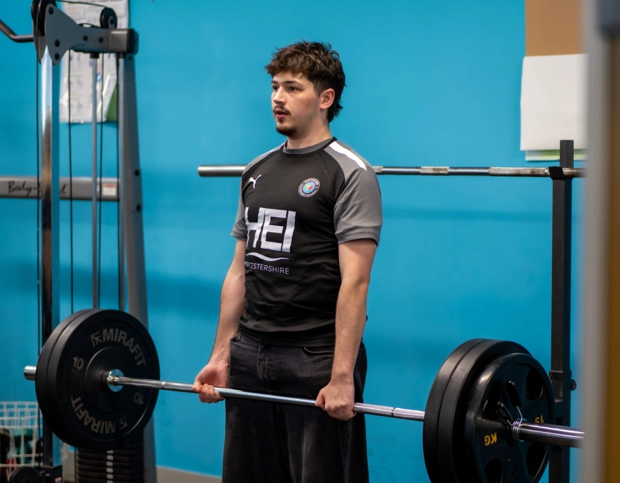 Student lifting a barbell in a gym