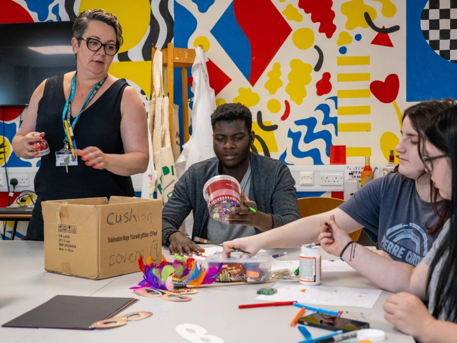 3 students and a teacher doing different arts and crafts in a classroom