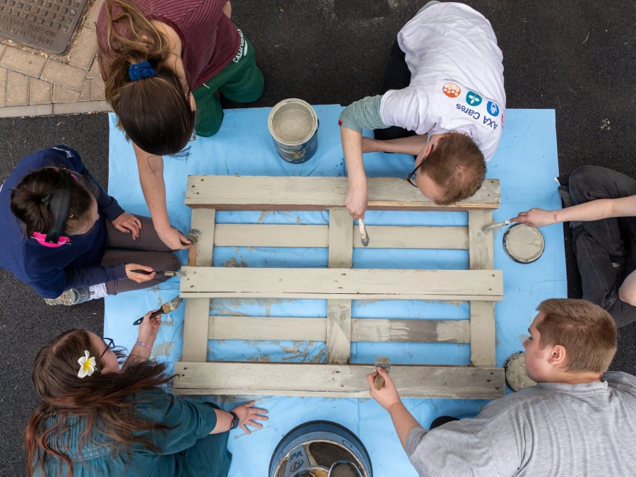 five students outside painting wood