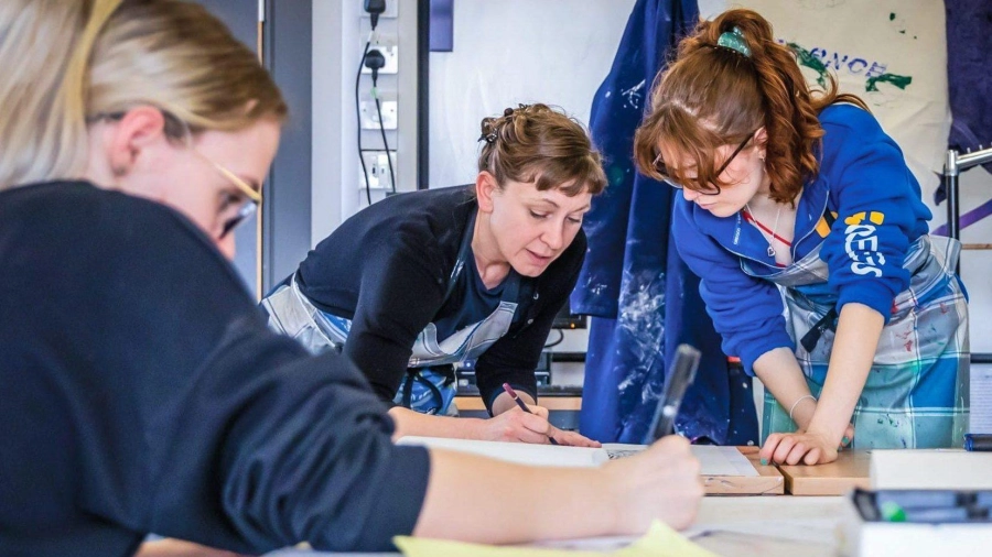 Two students and a tutor in an art classroom drawing