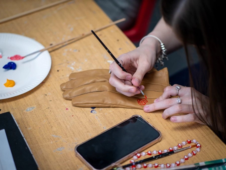 Student painting red onto a leather glove