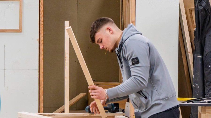 Apprentice holding wood in a workshop