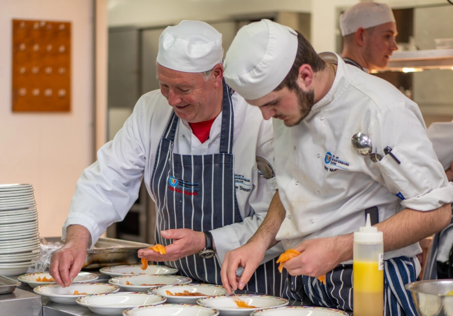 Tutor and student working in a kitchen together preparing meals