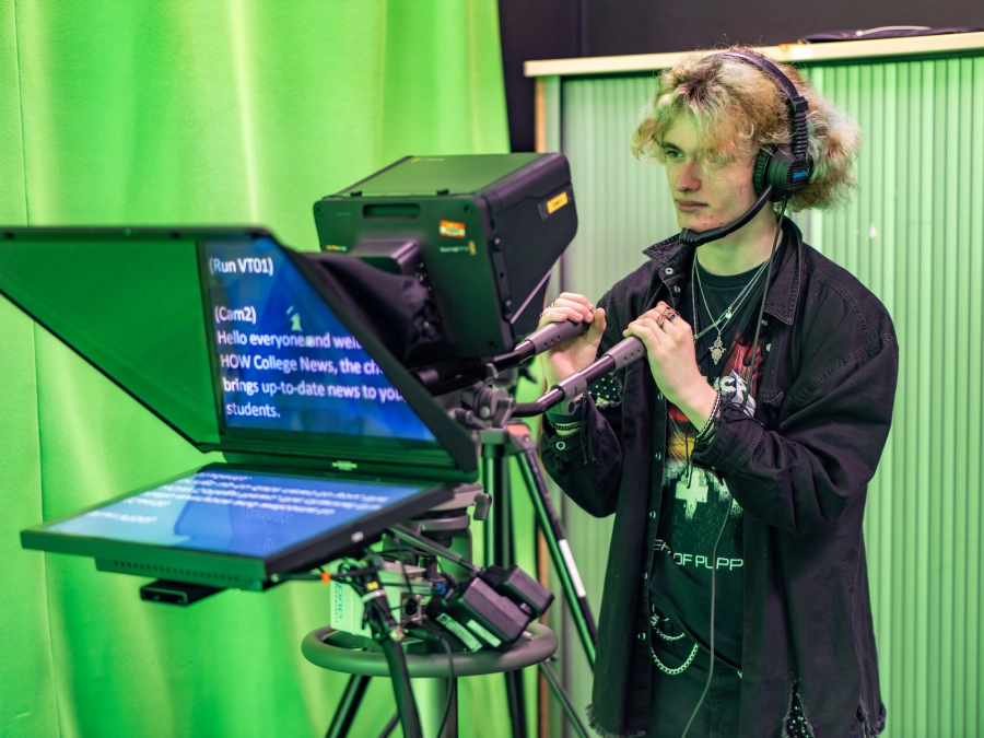 Student in a green screen room working with media production equipment