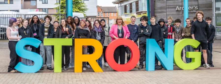 Principal and students stood in front of giant STRONG letters