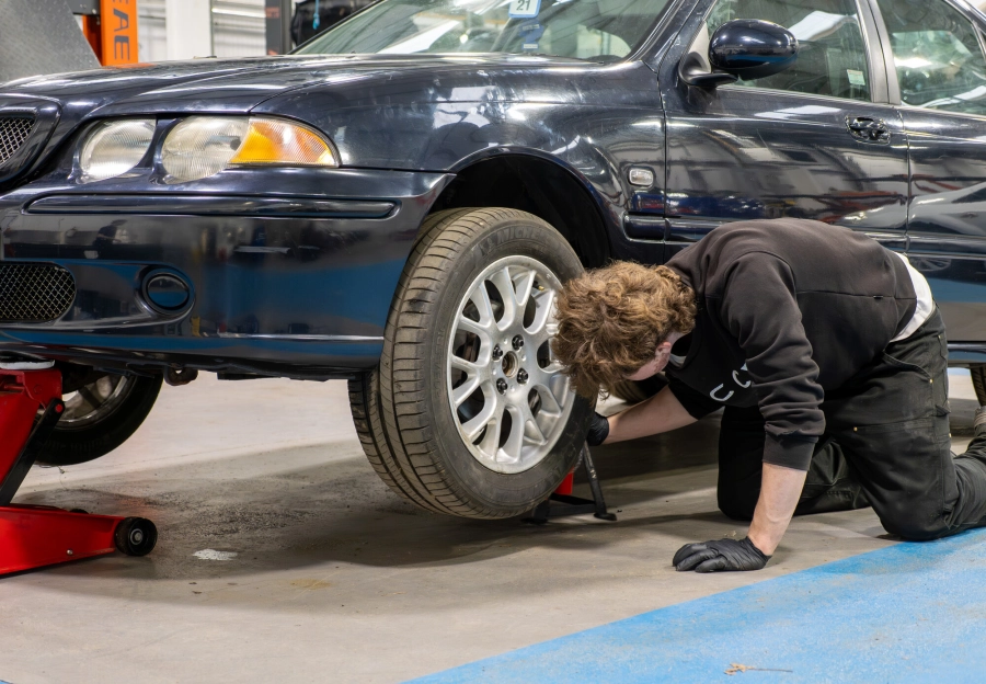 Apprentice working on a tyre of a car in an automotive workshop