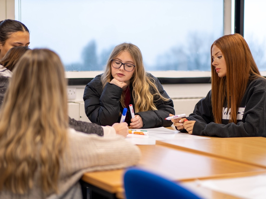Students sat round a table working together in a classroom
