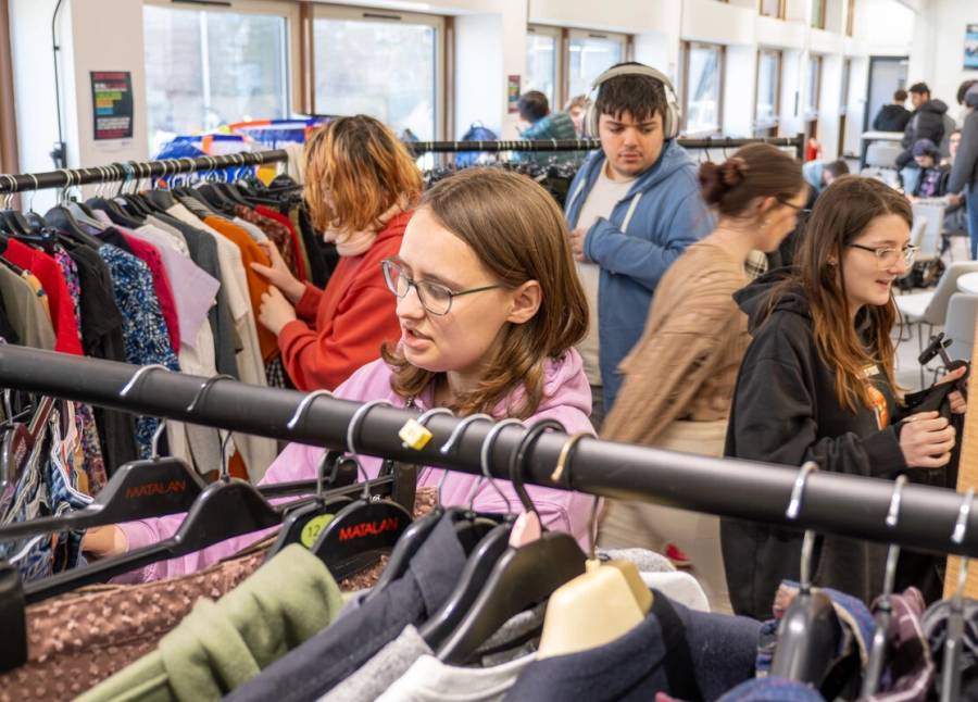 5 students browsing clothes on hangers at the swap shop event in Worcester.
