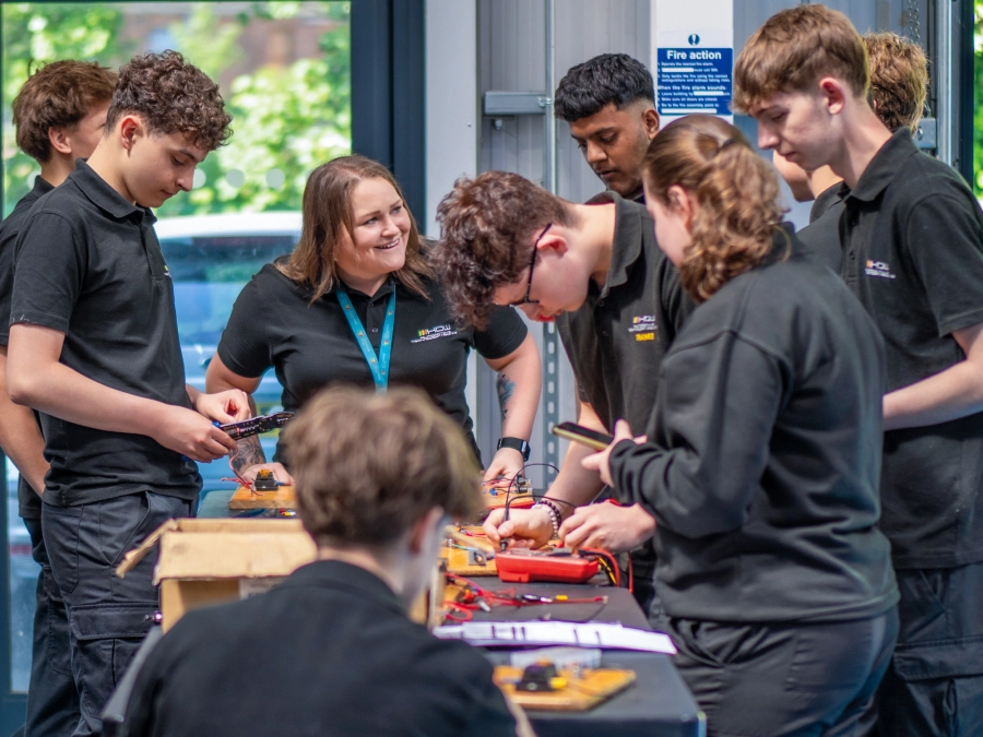 Students in an automotive lesson talking and working with the tutor