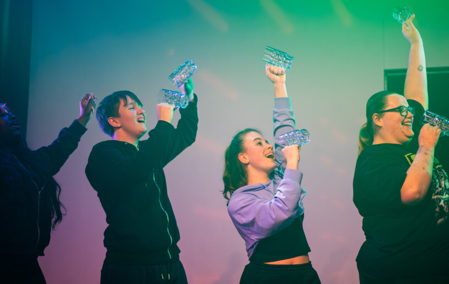 Three Performers stand together on a stage