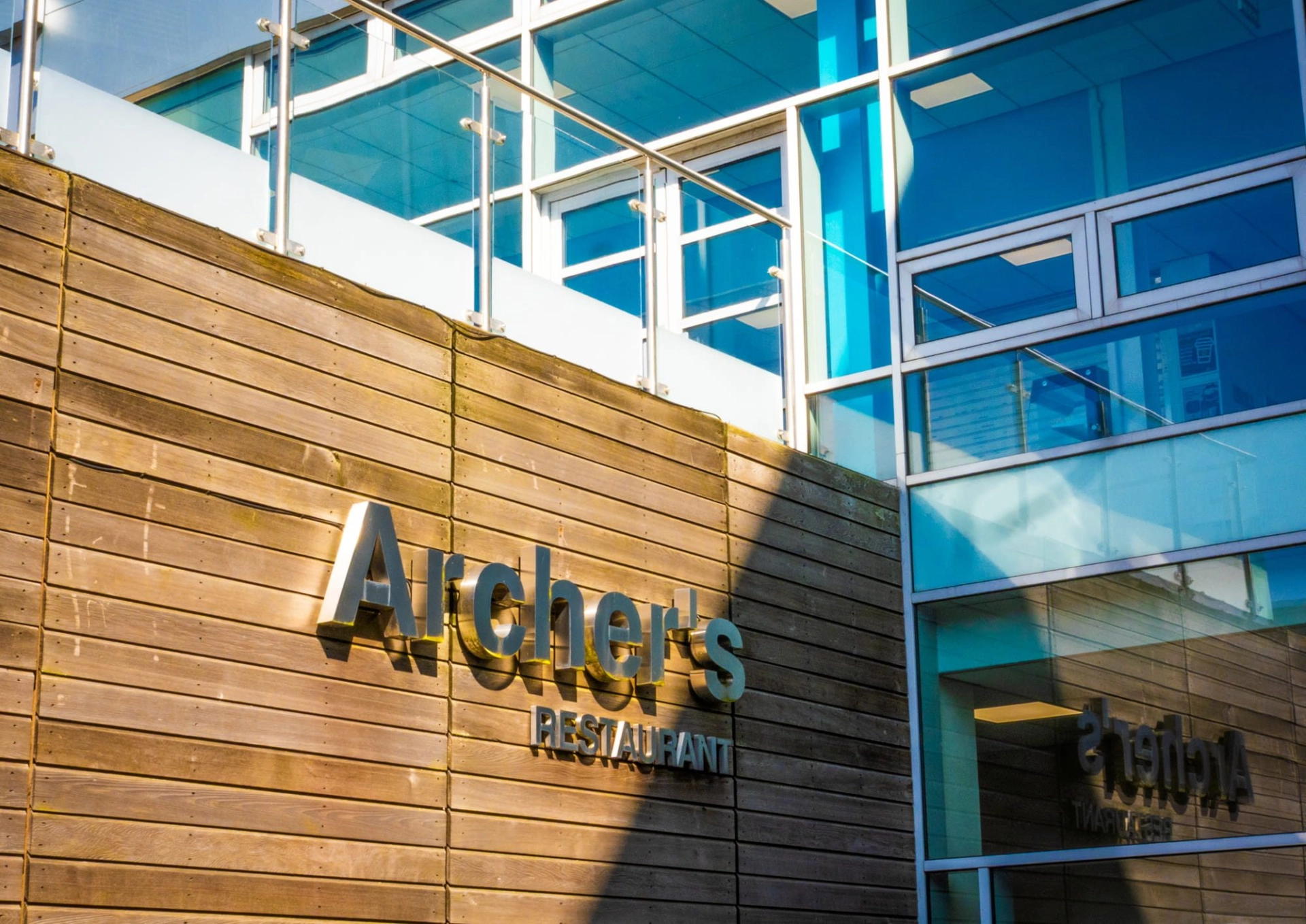 Archers Restaurant sign on a wooden wall with a glass building connected to it