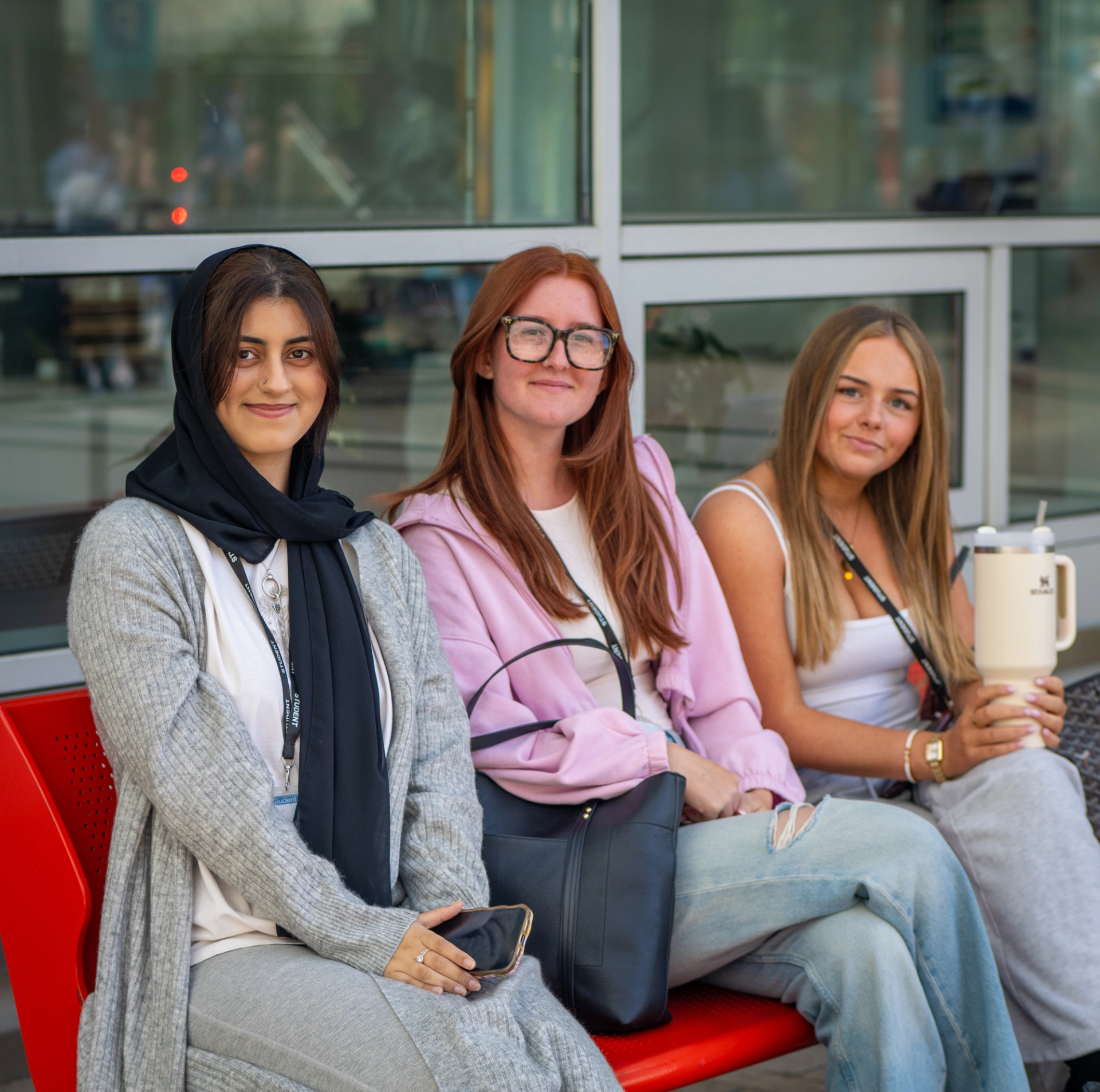 Three students sit together on a bench