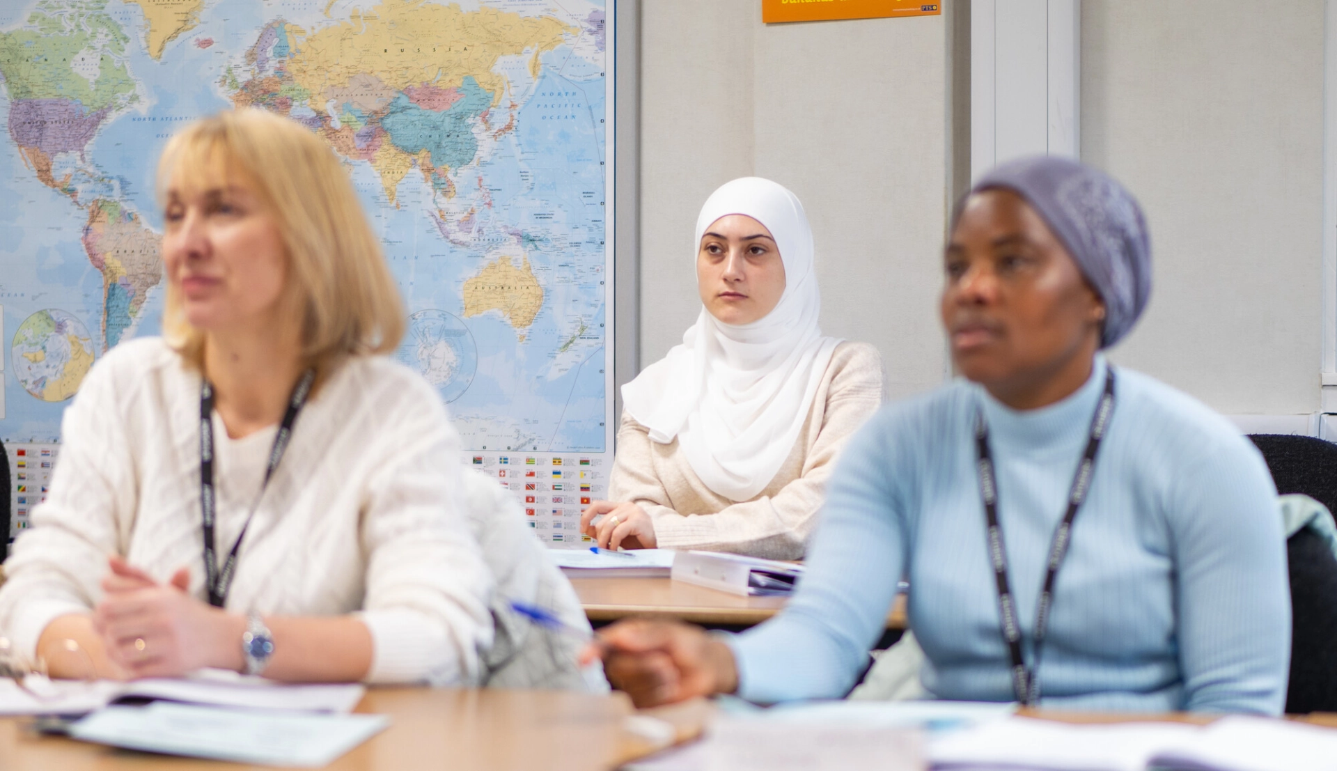 Three adult learners in a classroom during a lesson