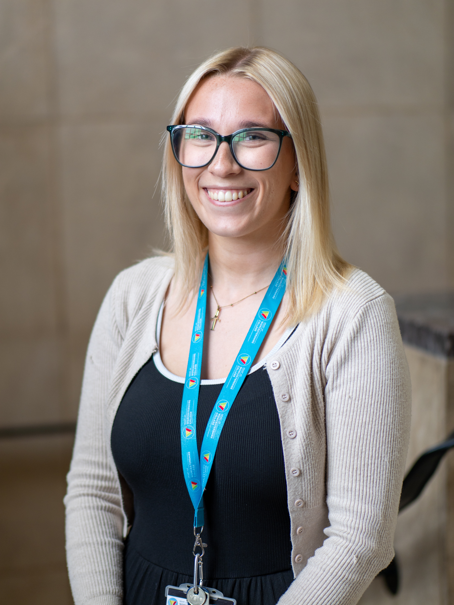 Picture HoW College staff member Lucy smiling in front of staircase