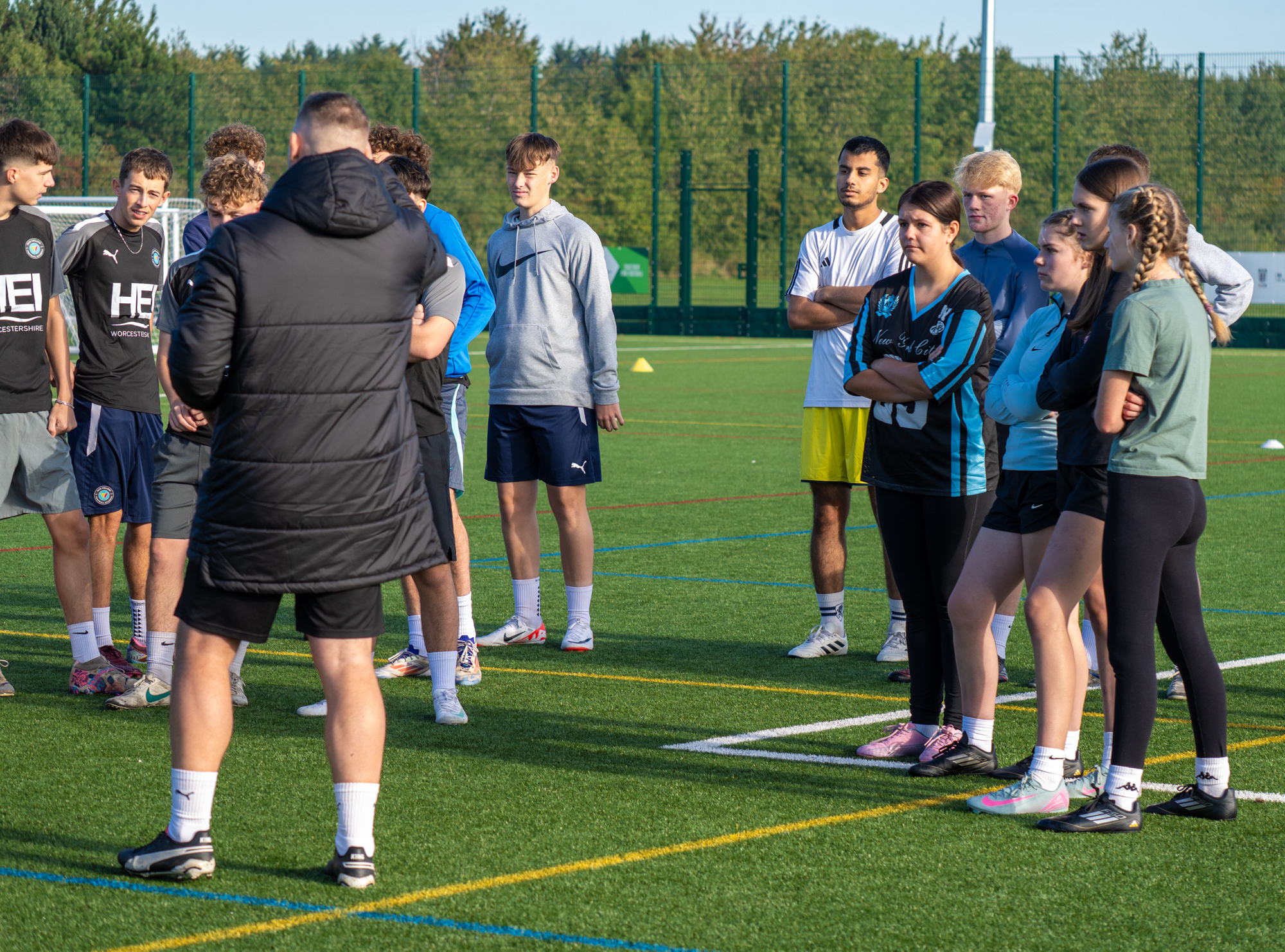 Sports students on a football field listening to their tutor