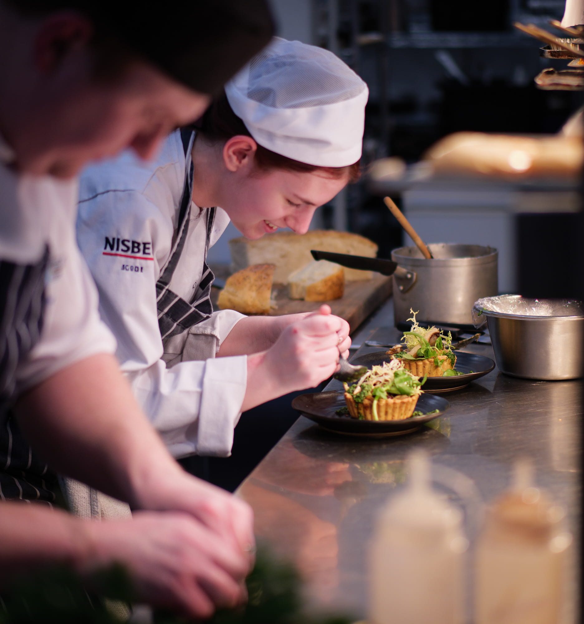 Students wearing chef whites preparing food